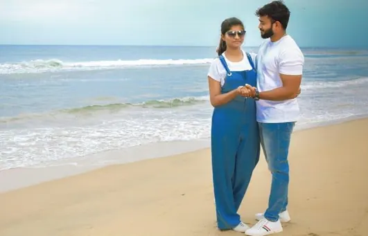 Couple in casual denim standing together on a beach for an outdoor couple shoot