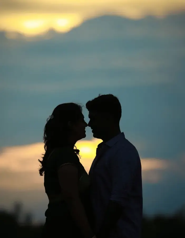 Silhouette of a couple about to kiss against a sunset sky
